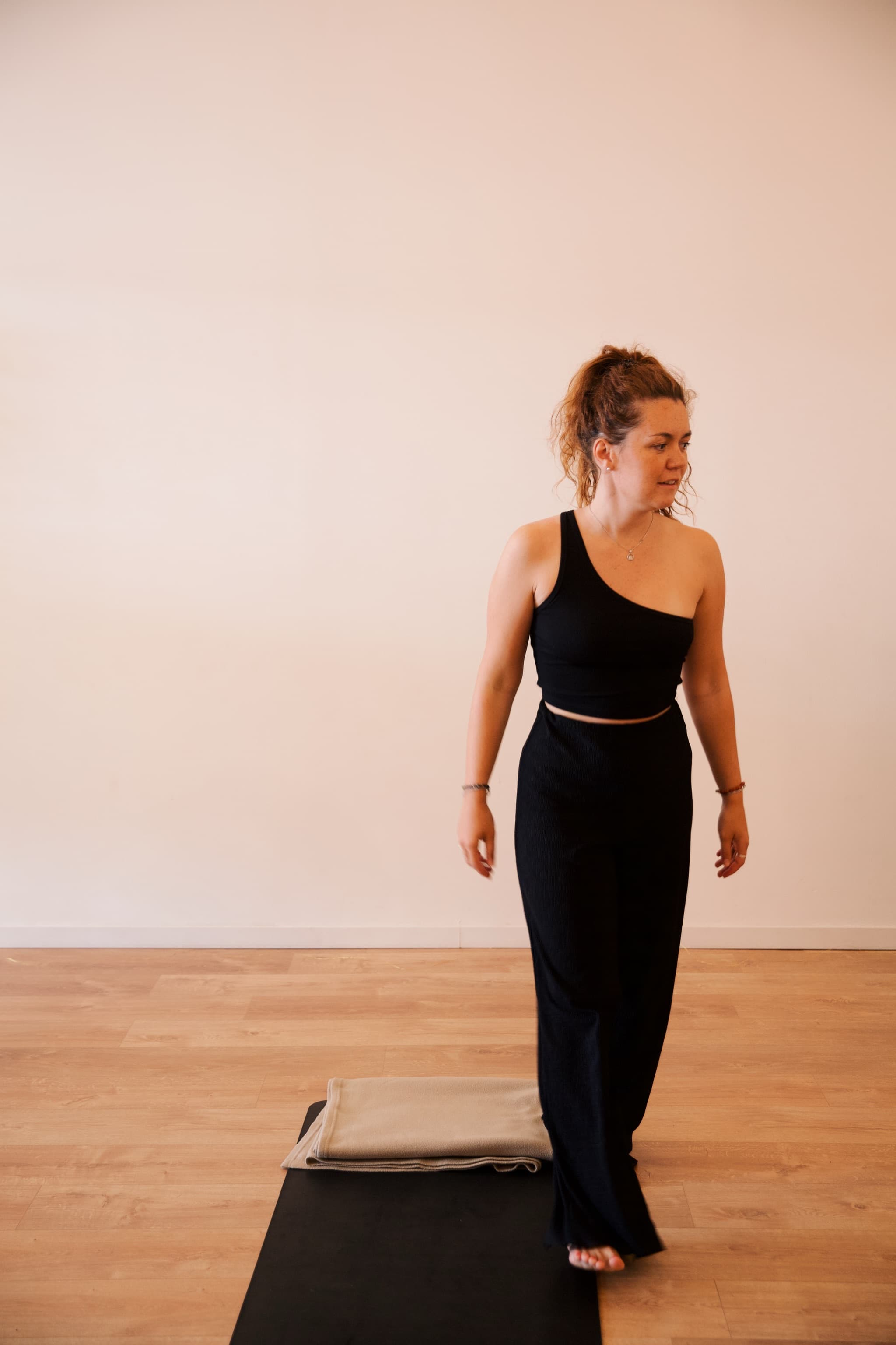 Une participante debout près de son tapis et de sa couverture
