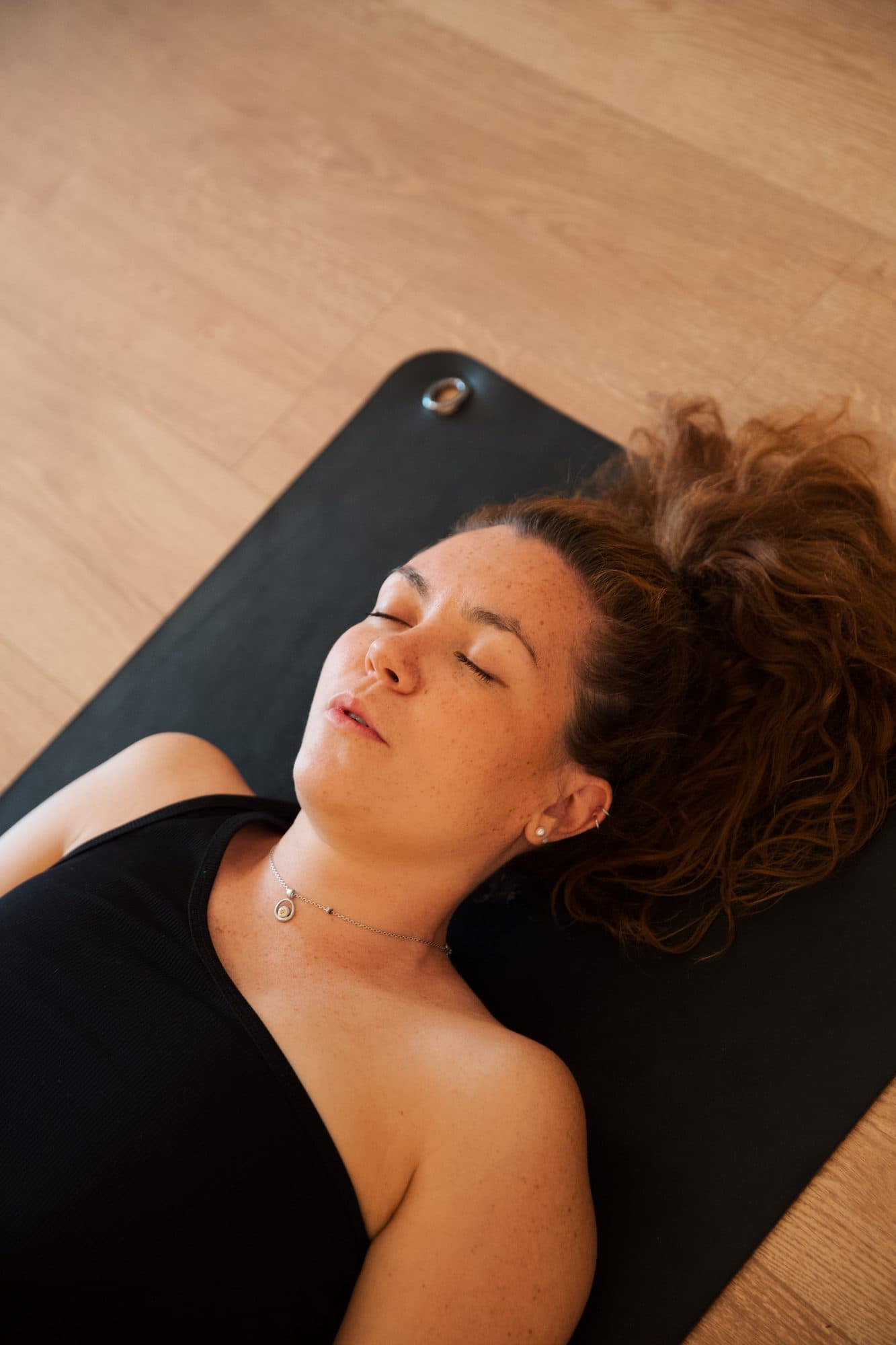Une participante allongée sur son tapis respire, les yeux fermés